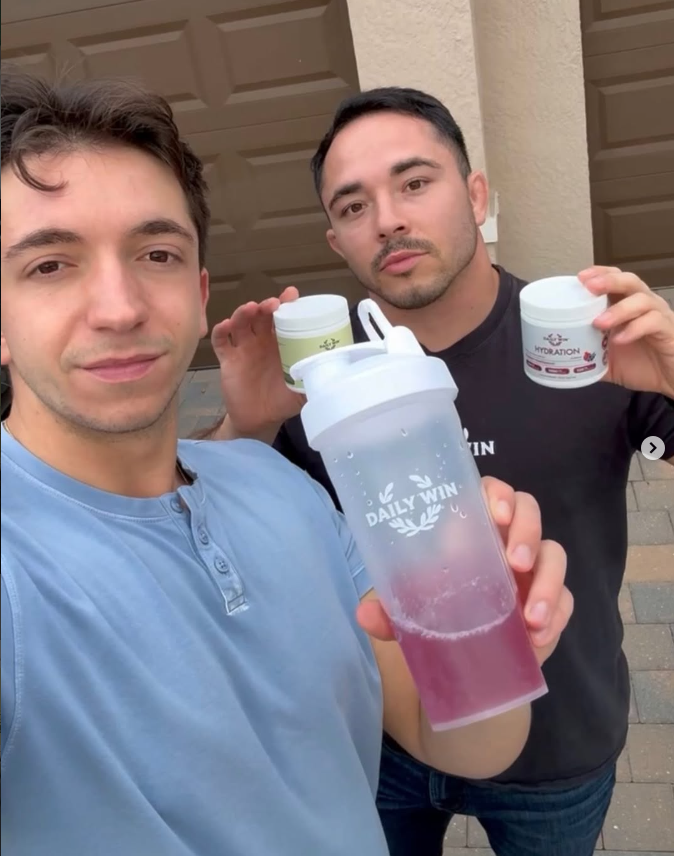 Daily Win co-founders Jacob and Dominic holding both flavor tubs and a branded shaker